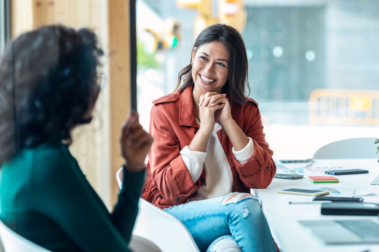 69f237ef4e91c63b69b07fc6_two-women-chatting-bright-office-comp